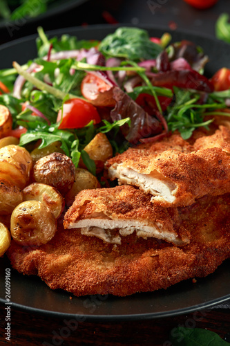 Homemade breaded pork schnitzel with roast potato and vegetables