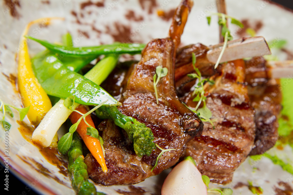 Roasted lamb chops with green pea purée, baby vegetables and classic mint sauce
