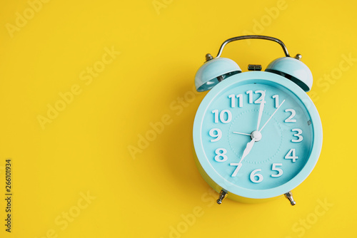 Alarm clock on yellow paper background. Minimal-concept.