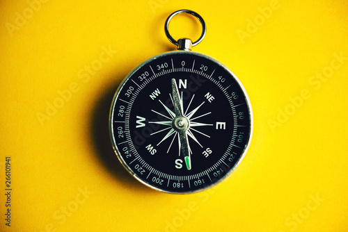 Compass on yellow background, minimal-travel-concept.