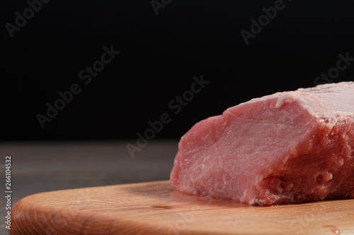 Raw pork tenderloin on a cutting board on a dark background