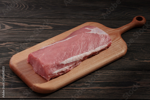 Whole boneless pork loin without fat. Pork tenderloin on a cutting board on a dark background