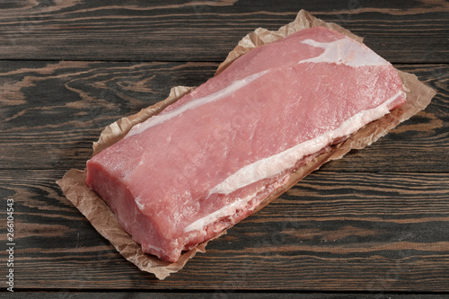 Whole boneless pork loin without fat. Pork tenderloin on paper on a dark background