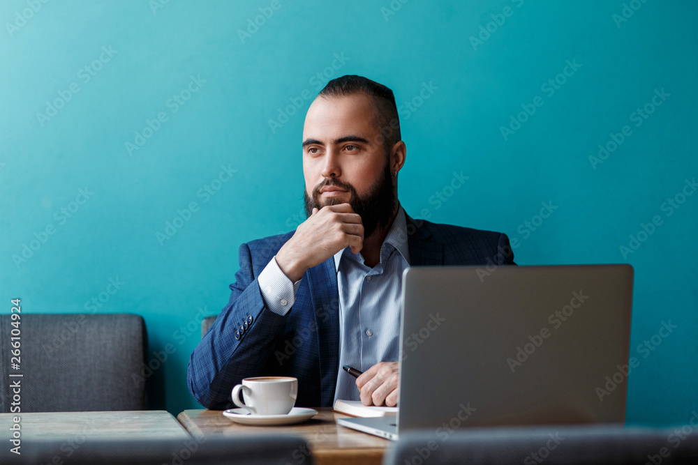 Businessman bearded man in a suit works behind the laptop sitting in a comfortable office coworking. Businessman bearded man in a suit works behind the laptop sitting in a comfortable office coworking.
