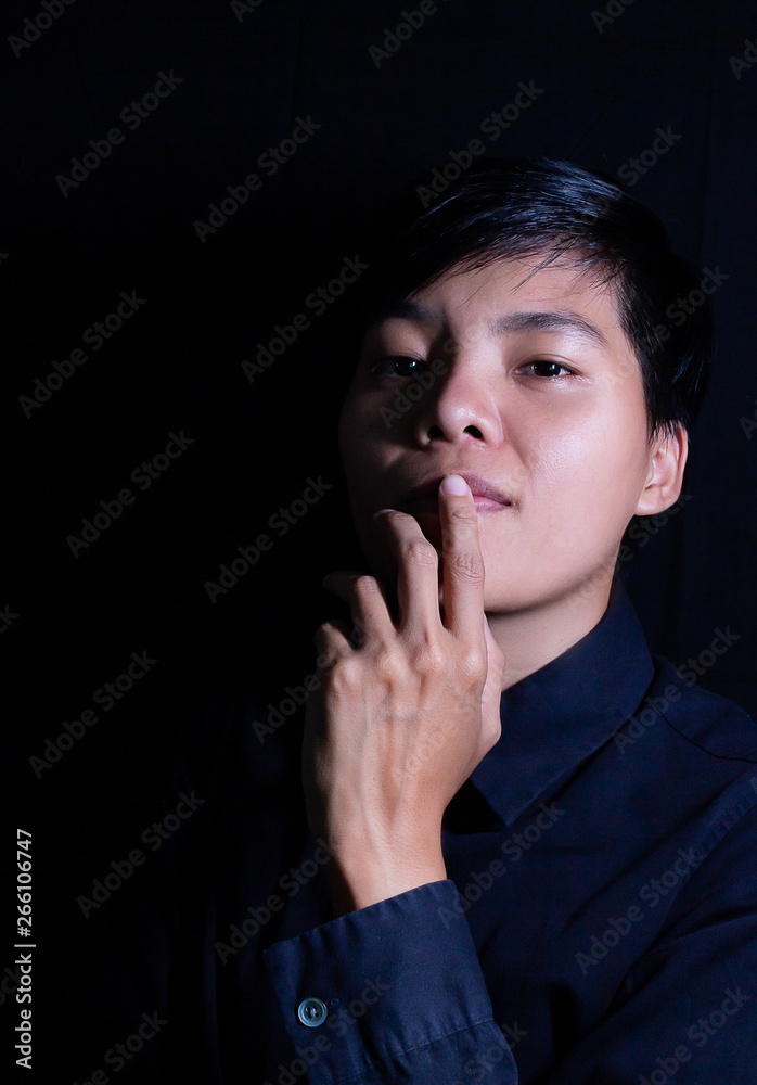 Studio portrait of a Thai Asian LGBT,women handsome beautiful young man standing on black backdrop is black shirt with feeling,think on face. Studio portrait of a Thai Asian LGBT,women handsome beautiful young man standing on black backdrop is black shirt with feeling,think on face.