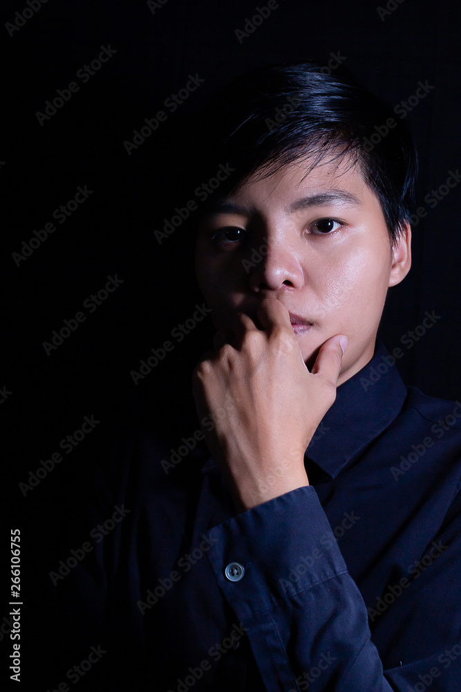 Studio portrait of a Thai Asian LGBT,women handsome beautiful young man standing on black backdrop is black shirt with feeling,think on face. Studio portrait of a Thai Asian LGBT,women handsome beautiful young man standing on black backdrop is black shirt with feeling,think on face.