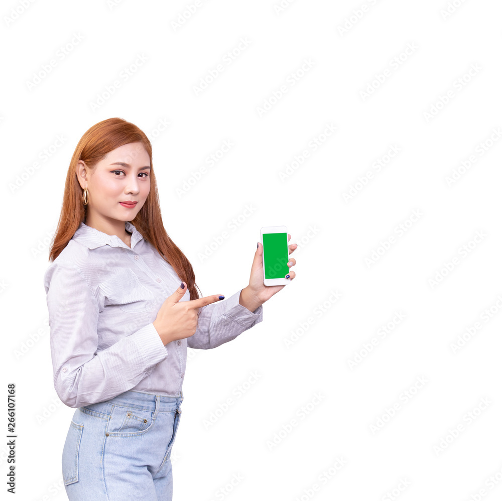 smiling Asian woman standing in casual shirt holding mobile phone and pointing on smartphone isolated on white background with clipping path smiling Asian woman standing in casual shirt holding mobile phone and pointing on smartphone isolated on white background with clipping path