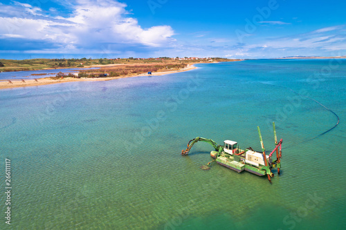 Fototapeta Naklejka Na Ścianę i Meble -  Dredger boat excavating sand for beach in shallow water near town of Nin