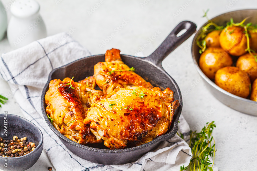 Grilled chicken and baked potatoes in a cast iron skillet. Grilled chicken and baked potatoes in a cast iron skillet.