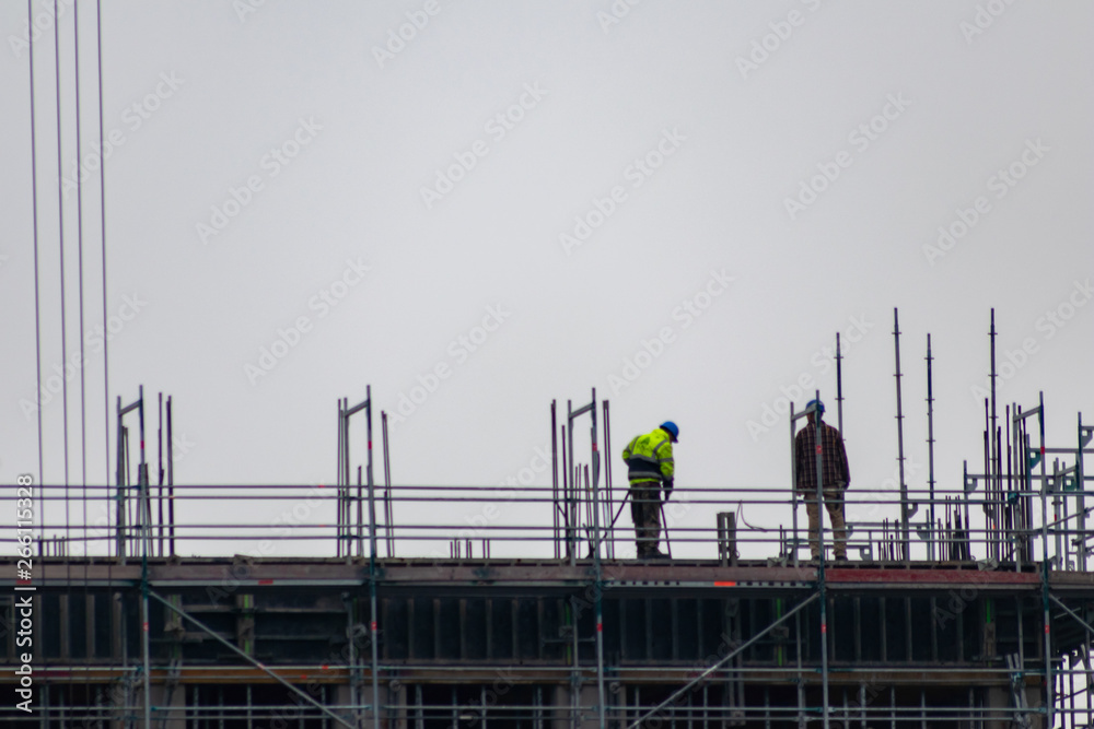 Bauarbeiter hoch oben auf einer Baustelle bereiten die Konstruktion vor Bauarbeiter hoch oben auf einer Baustelle bereiten die Konstruktion vor