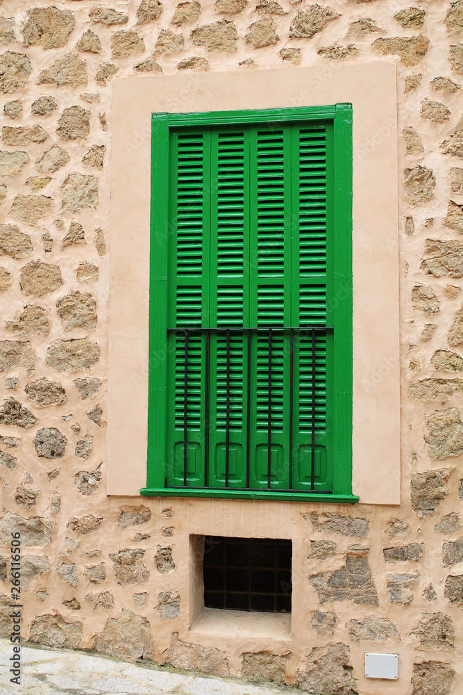 green window shutters in a stone wall