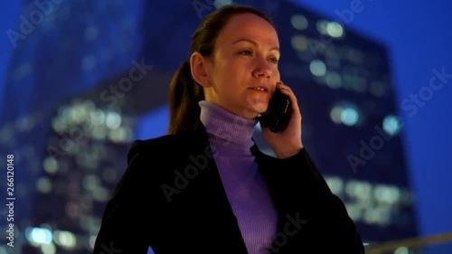 Busy Woman talking on cellphone against modern skyscraper at city downtown