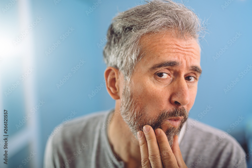 closeup of middle aged bearded gray haired man looking at the mirror closeup of middle aged bearded gray haired man looking at the mirror