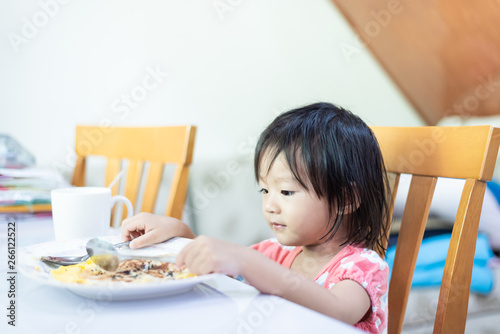 Asian little baby child eating and enjoy breakfast by herself photo