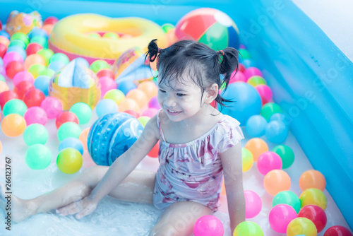little children enjoy and have fun playing water in inflatable pool with colorful of small balls