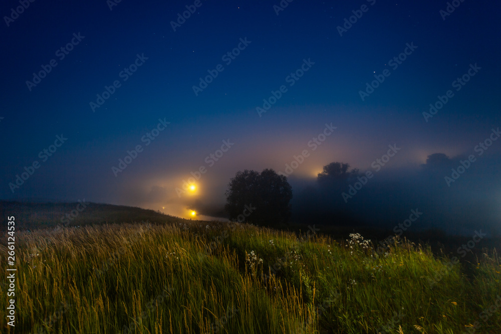 Fog over the night river in the village under the star sky
