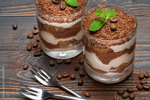 two portions Classic tiramisu dessert in a glass on wooden background