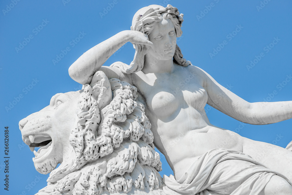 Ancient statue sensual renaissance era woman laying on big lion in Potsdam, Germany