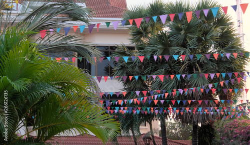 Many multicolored flags decorate the street. Decorative garlands. Tropical trees. photo