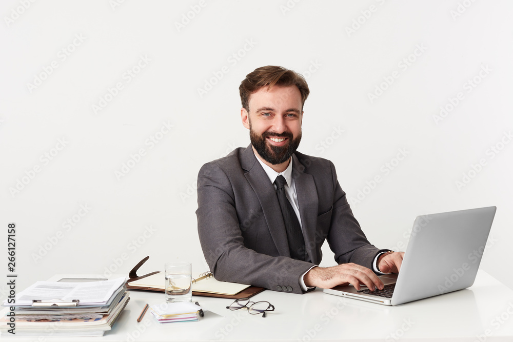 Portrait of a young successful businessman working at his laptop and smiling at the camera. Portrait of a young successful businessman working at his laptop and smiling at the camera.