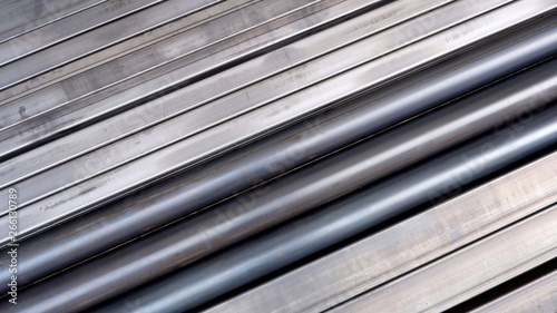 Diagonal view of carbon steel pipes and many rectangular steel tubes on the floor for background design in construction and industrial concept, top view with copy space