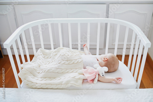 Baby sleeping in co-sleeper crib attached to parents' bed photo