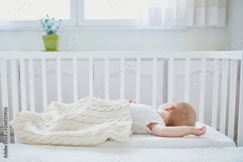 Baby sleeping in co-sleeper crib attached to parents' bed photo