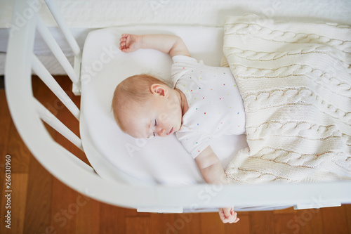 Baby sleeping in co-sleeper crib attached to parents' bed photo