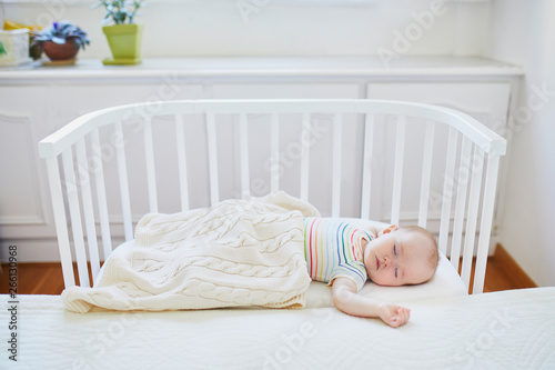 Baby sleeping in co-sleeper crib attached to parents' bed