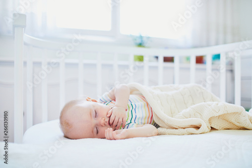 Baby sleeping in co-sleeper crib attached to parents' bed photo