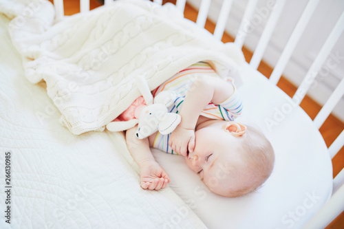 Baby sleeping in co-sleeper crib attached to parents' bed photo