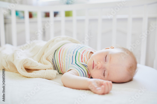 Baby sleeping in co-sleeper crib attached to parents' bed photo