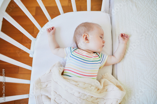 Baby sleeping in co-sleeper crib attached to parents' bed photo