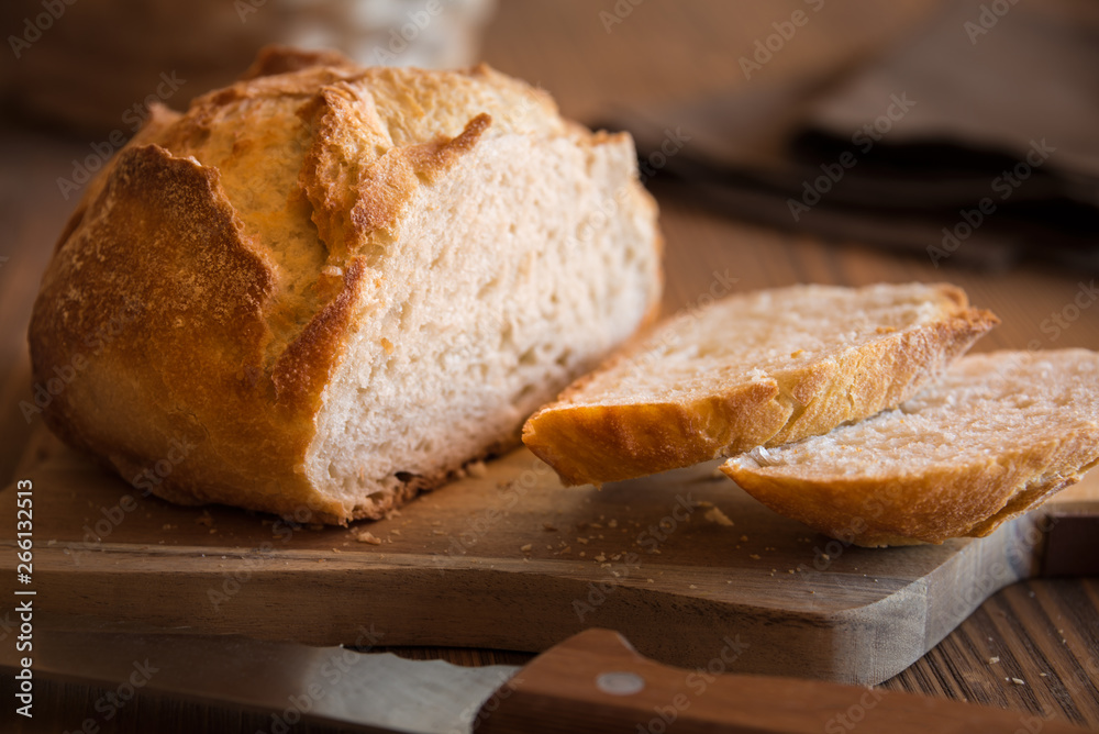 Sliced loaf of wheat bread on wooden table