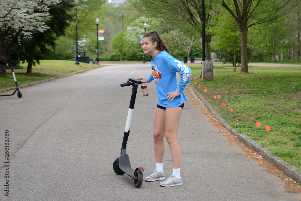 Naklejka premium Girl Riding Electric Scooter in Park