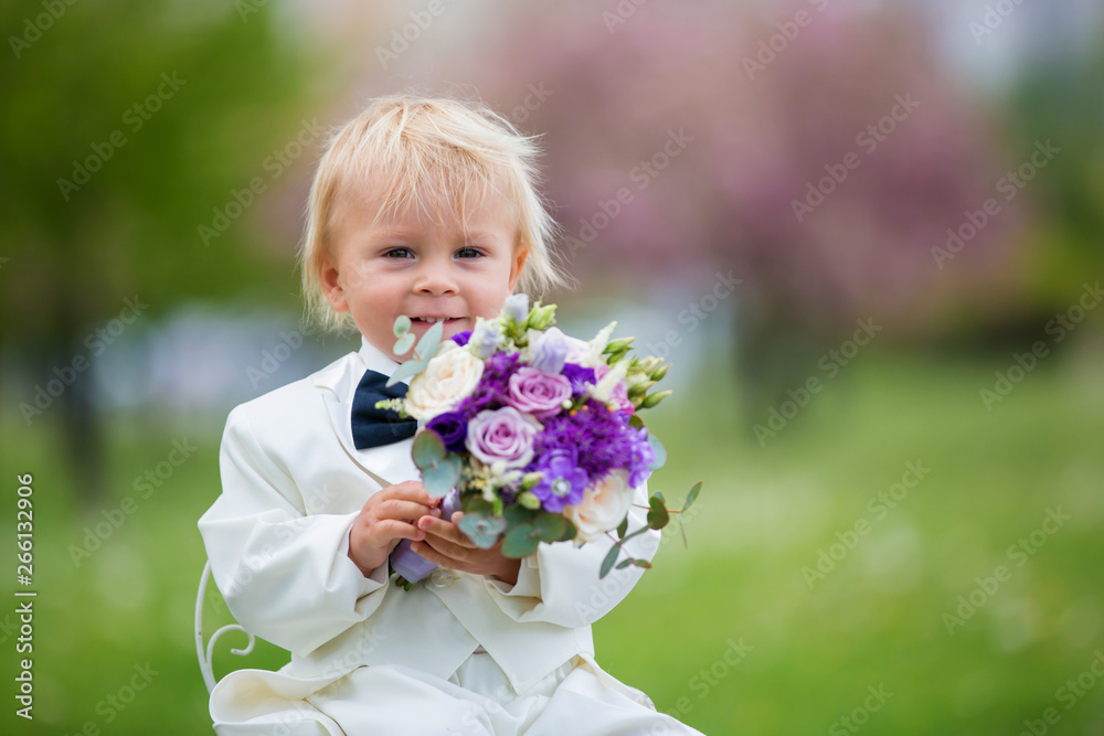 Beautiful toddler boy, dressed in white tuxedo, holding gorgeous flower bouquet for mothers day Beautiful toddler boy, dressed in white tuxedo, holding gorgeous flower bouquet for mothers day