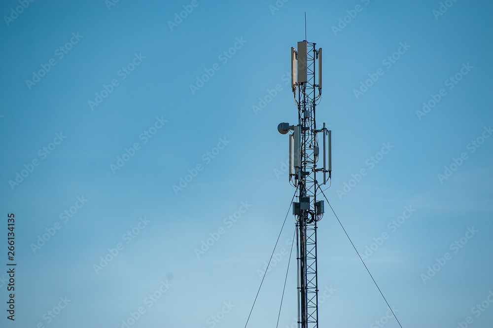 4G and 5G cell site. Telecommunications. City tower cells for mobile communications. Base transceiver station and wireless communication antenna transmitter on antennas against blue sky.
