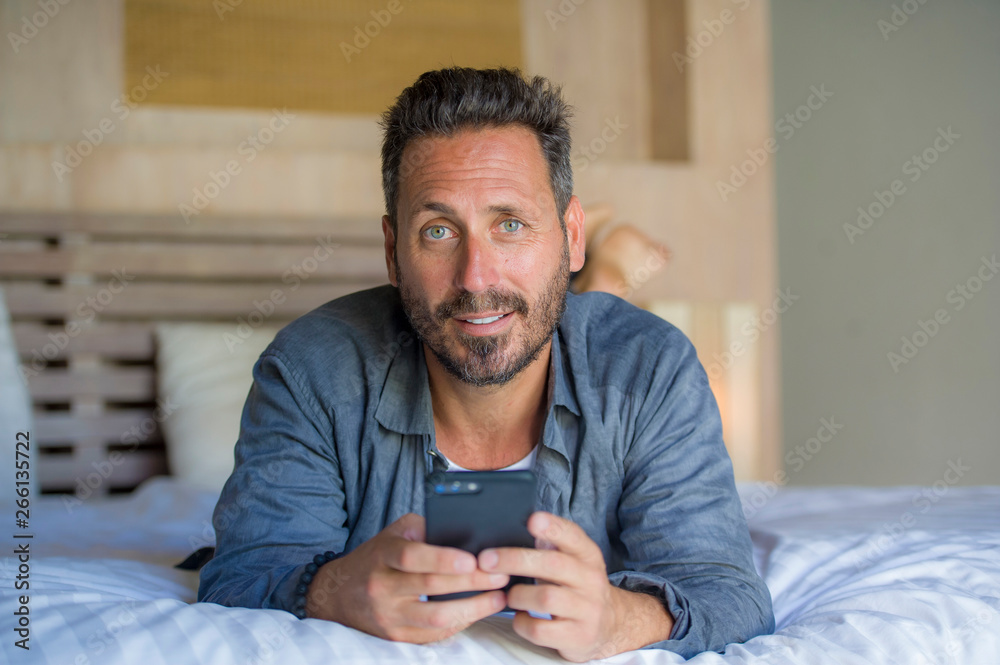 young handsome and happy man at home using internet mobile phone on bed smiling cheerful and satisfied feeling relaxed dating online or enjoying social media app