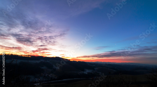colorful sunset with glowing clouds and a tree a hill and valley silhouette in the austrian alps © woitzel
