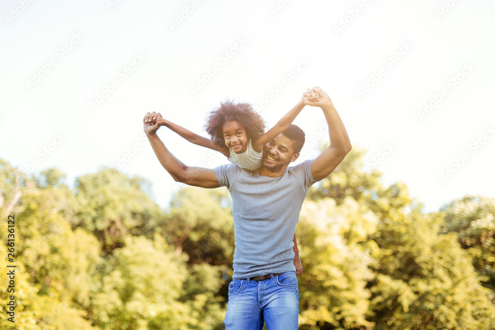 Portrait of young father carrying his daughter on his back Portrait of young father carrying his daughter on his back