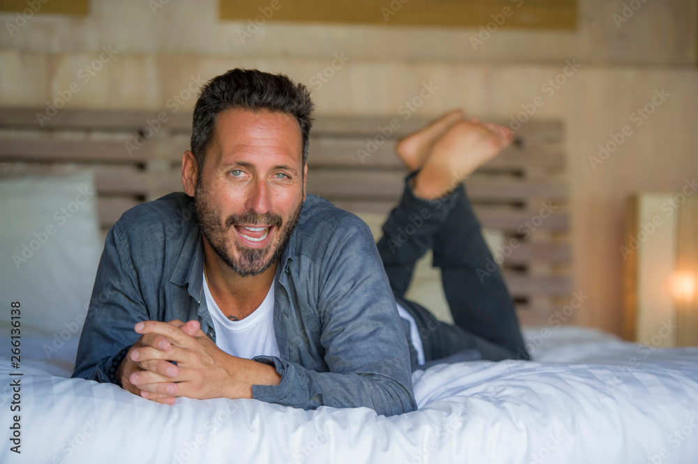 30s happy and handsome man at home in casual shirt and jeans lying on bed relaxed at home smiling confident and happy feeling positive in male lifestyle concept 30s happy and handsome man at home in casual shirt and jeans lying on bed relaxed at home smiling confident and happy feeling positive in male lifestyle concept