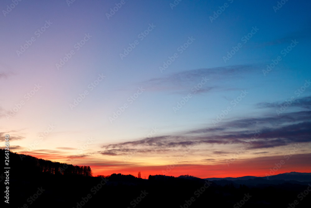 colorful sunset with glowing clouds and a tree a hill and valley silhouette in the austrian alps colorful sunset with glowing clouds and a tree a hill and valley silhouette in the austrian alps