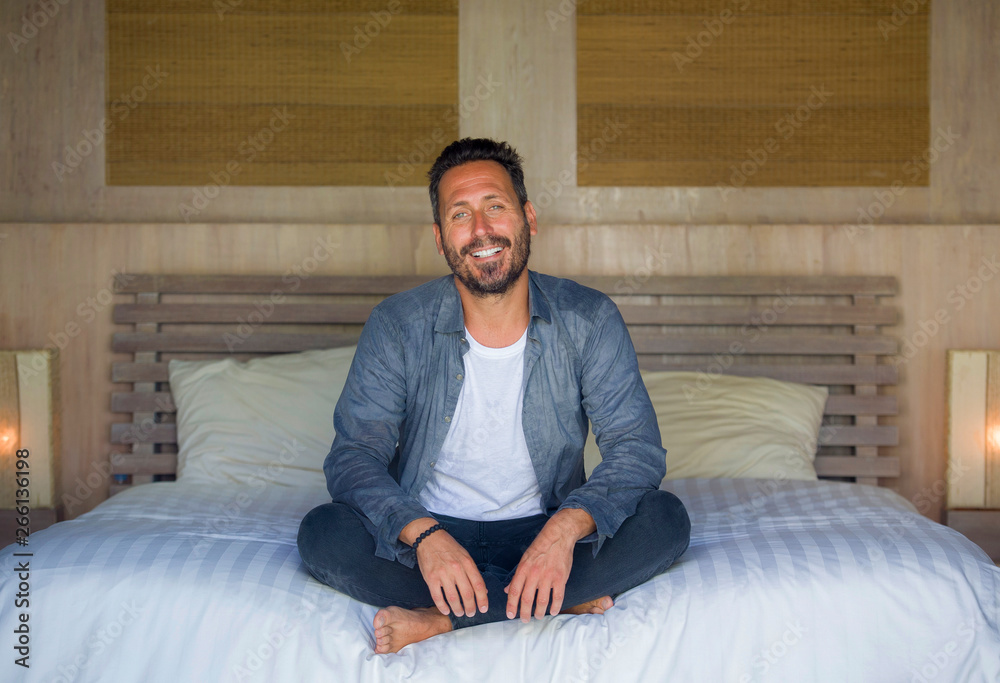 interior portrait of 30s happy and handsome man at home in casual shirt and jeans sitting on bed relaxed at home smiling confident and happy feeling positive interior portrait of 30s happy and handsome man at home in casual shirt and jeans sitting on bed relaxed at home smiling confident and happy feeling positive