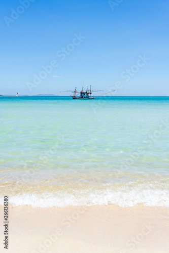 Beautiful bay with fisherman boat on the blue sky background. Tropical sand beach and sea water on the island Koh Phangan, Thailand