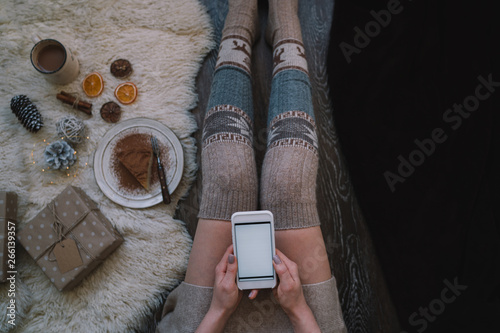 Woman using smartphone for browsing internet store at home. Online shopping conceptspace for text. Mood winter. Seasonal holidays. Merry Christmas and New Year. Top view. Toned image. Selective focus. photo