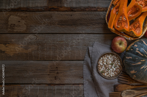 Fresh organic vegetables on rustic wooden background. Healthy natural food. Sliced and whole pumpkins with seed. Cooking ingredients. Autumn seasonal eating. Rural still life. Top view. Toned image.