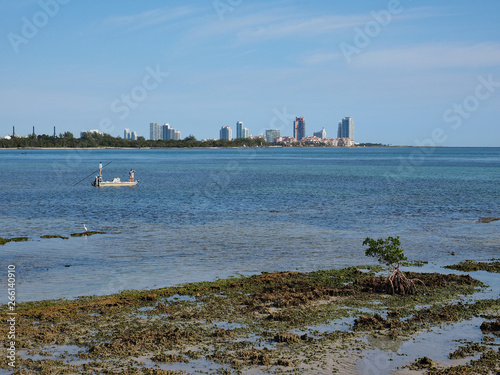 Fishermen off the Fossilized Reef in Bear Cut on Key Biscayne, Florida, at low tide with buildings of Miami Beach in the background.