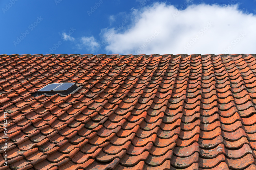 An old roof with burnt tiles. Roof in village house against a blue sky background An old roof with burnt tiles. Roof in village house against a blue sky background