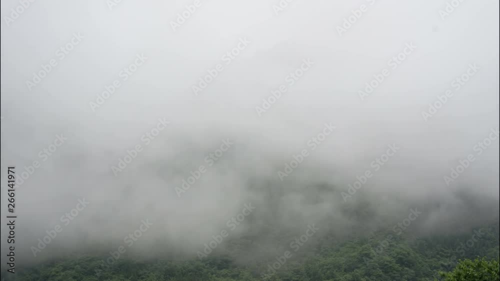 Timelapse of clouds over mountain peaks China. Ancient mountain cloudy time lapse drifting on Chinese forested hills on overcast rainy day. Cloudy mist billows across forest covered peaks. Timelapse of clouds over mountain peaks China. Ancient mountain cloudy time lapse drifting on Chinese forested hills on overcast rainy day. Cloudy mist billows across forest covered peaks.