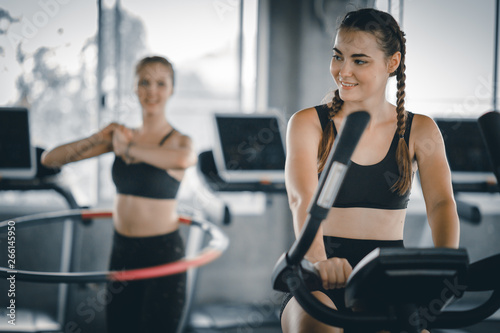 Attractive woman biking in the gym, exercising legs doing cardio workout cycling bikes. Fitness club with training exercise bikes. Fitness, Healthy, Sport, Lifestyle concept. © Shutter B